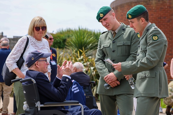 A couple of Royal Marines in lovats from 47 Commando chat with a Normandy veteran